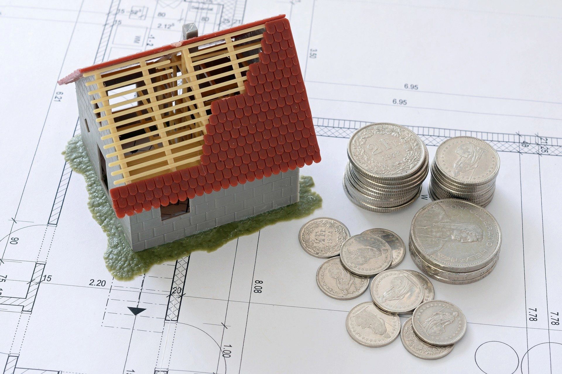 Model house with coins on a blueprint