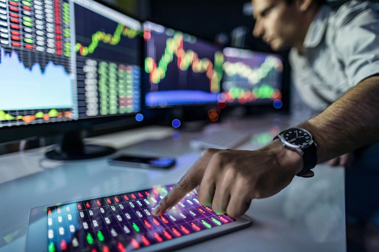 Hand on a keyboard in front of market screens