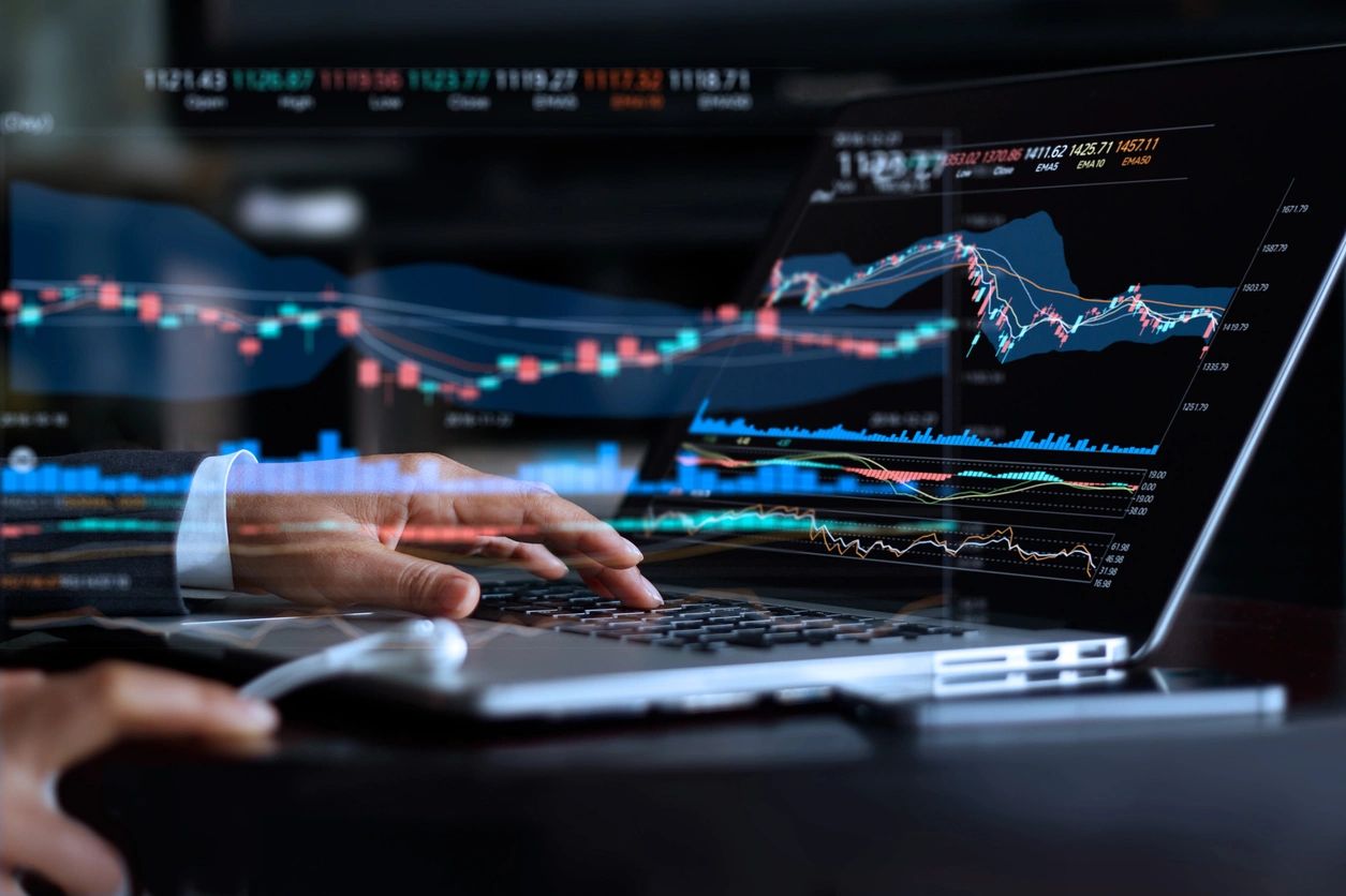 Hands typing on a laptop showing market data